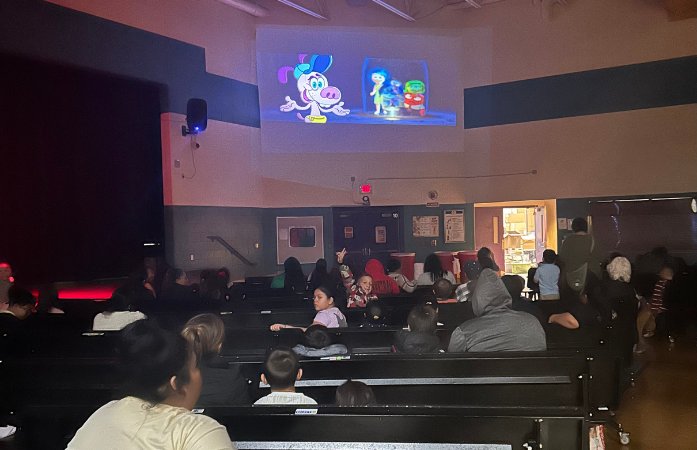 families sitting in the cafeteria watching a movie 